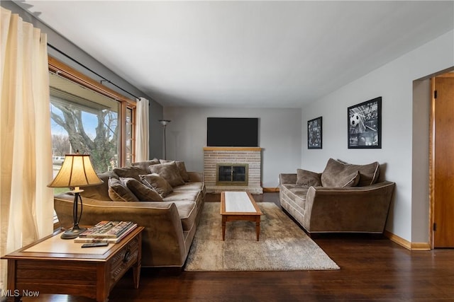 living room featuring dark wood-type flooring and a brick fireplace