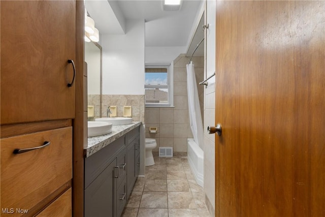 full bathroom featuring tile patterned flooring, toilet, shower / tub combo with curtain, vanity, and tile walls