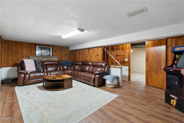 living room featuring wooden walls, brick wall, and hardwood / wood-style flooring