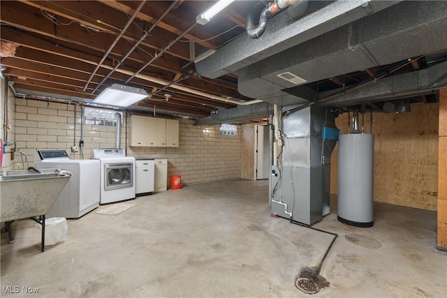 basement with washing machine and dryer, gas water heater, heating unit, and sink