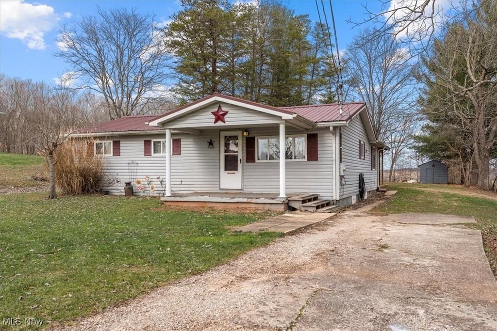 view of front facade featuring a front yard, a porch, and a shed