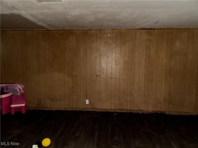 unfurnished room with dark hardwood / wood-style floors and wood walls