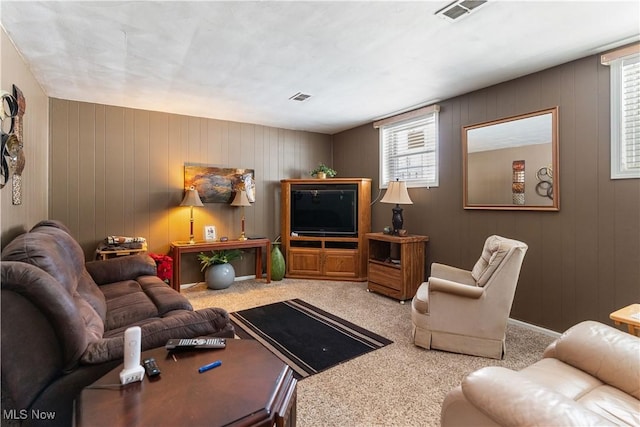 carpeted living room featuring wood walls