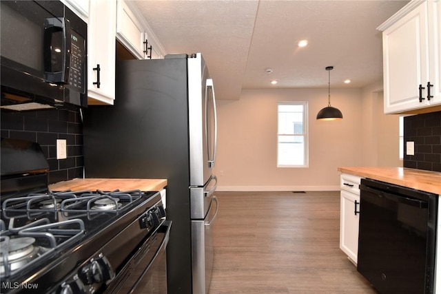 kitchen featuring decorative light fixtures, white cabinetry, butcher block counters, and black appliances