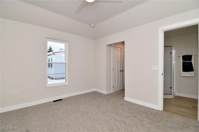 unfurnished bedroom with ceiling fan, light colored carpet, and a textured ceiling