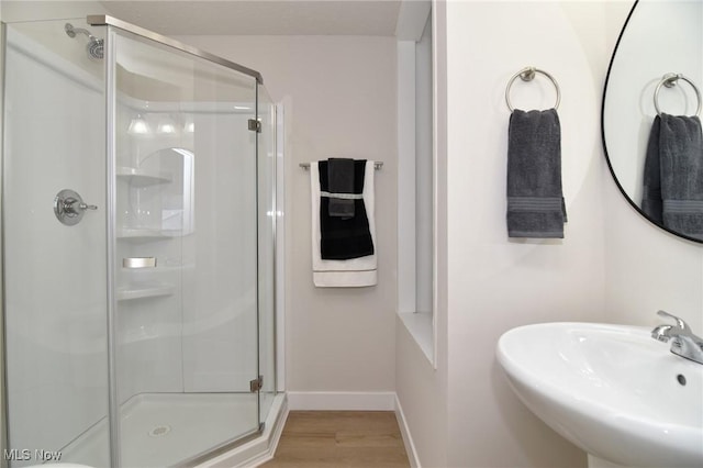 bathroom with sink, a shower with shower door, and hardwood / wood-style flooring