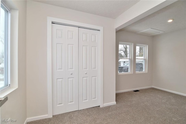 unfurnished bedroom featuring light carpet, a textured ceiling, and a closet