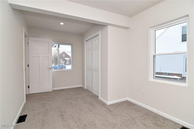 unfurnished bedroom featuring a closet and light colored carpet