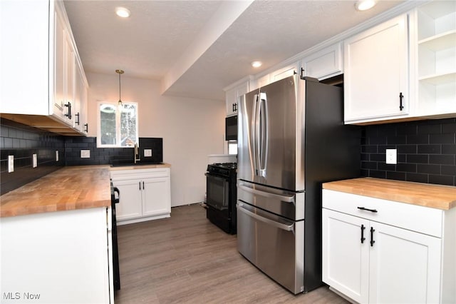 kitchen with butcher block countertops, pendant lighting, white cabinets, and black appliances