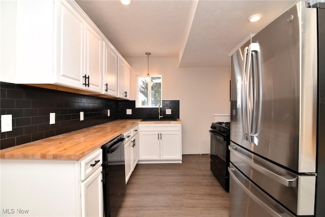 kitchen with butcher block counters, white cabinetry, hanging light fixtures, and black appliances