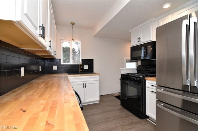 kitchen with pendant lighting, wood counters, white cabinets, and black appliances