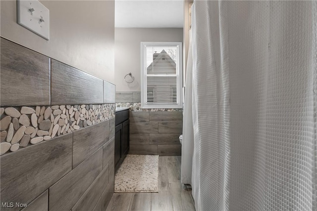 bathroom with wood-type flooring, vanity, and tile walls