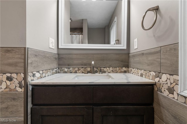 bathroom with vanity and tile walls