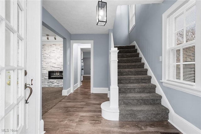 staircase featuring a large fireplace, rail lighting, plenty of natural light, and hardwood / wood-style flooring