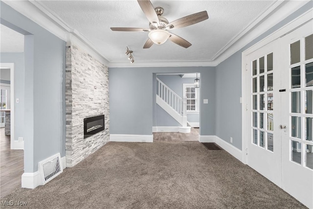 unfurnished living room featuring carpet flooring, french doors, a textured ceiling, and ornamental molding