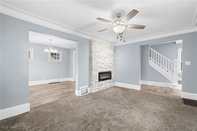 unfurnished living room featuring crown molding, a fireplace, carpet, and ceiling fan with notable chandelier