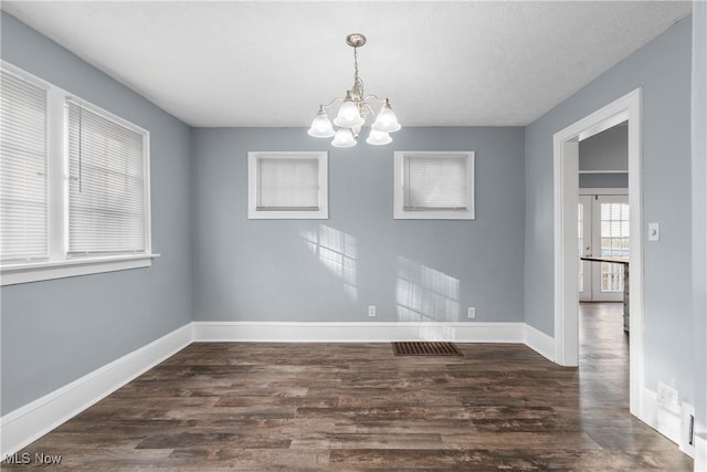 unfurnished dining area with dark hardwood / wood-style flooring and a chandelier