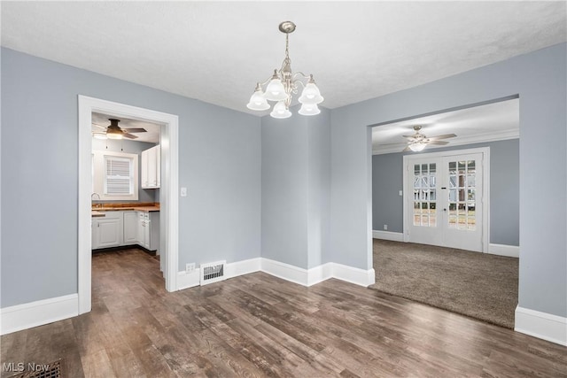 unfurnished dining area featuring french doors, ceiling fan with notable chandelier, crown molding, sink, and dark hardwood / wood-style floors