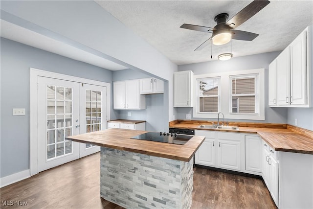 kitchen with butcher block countertops, black electric cooktop, white cabinets, and dark hardwood / wood-style floors