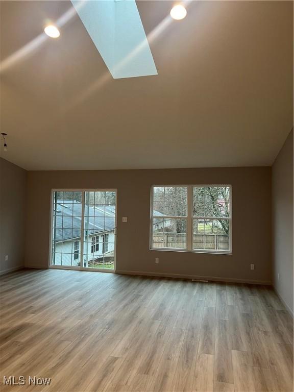 unfurnished living room with a skylight and light hardwood / wood-style flooring