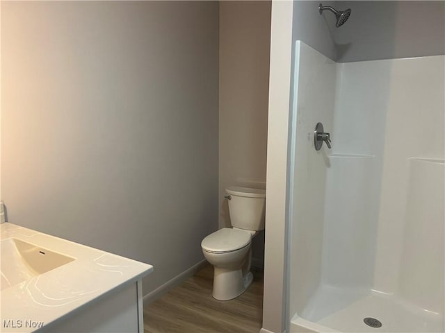 bathroom with toilet, hardwood / wood-style floors, a shower, and vanity