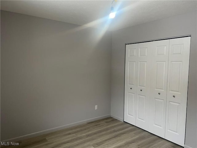 unfurnished bedroom with light hardwood / wood-style floors and a closet