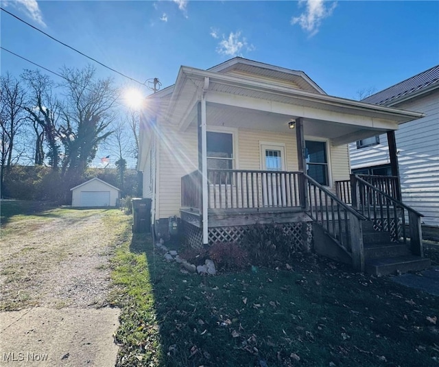 bungalow featuring a porch, a garage, and an outbuilding