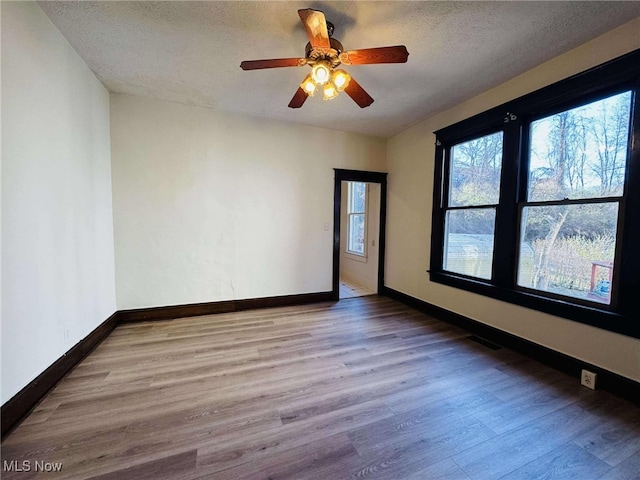 unfurnished room featuring ceiling fan, a textured ceiling, and light hardwood / wood-style flooring