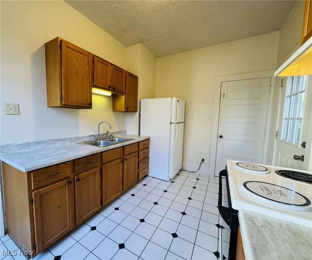 kitchen with a textured ceiling, white appliances, light tile patterned floors, and sink