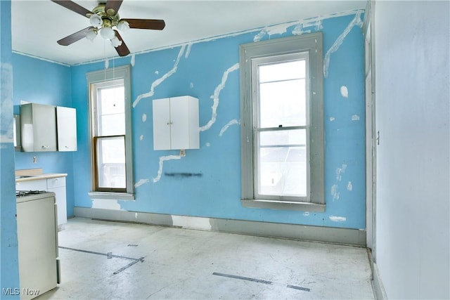 empty room featuring ceiling fan and baseboards