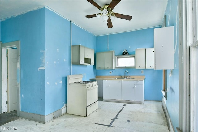kitchen featuring white range with gas cooktop, a sink, ceiling fan, and light countertops