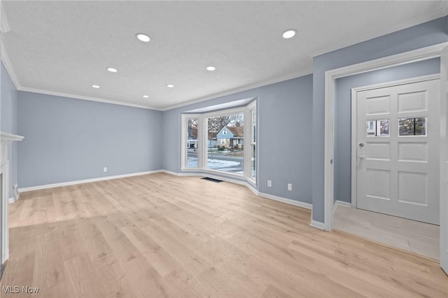 unfurnished living room featuring a textured ceiling, light wood-type flooring, and ornamental molding