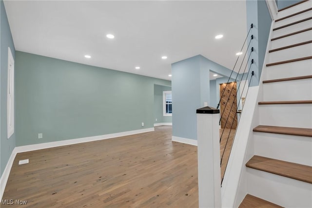 stairs featuring baseboards, wood finished floors, and recessed lighting