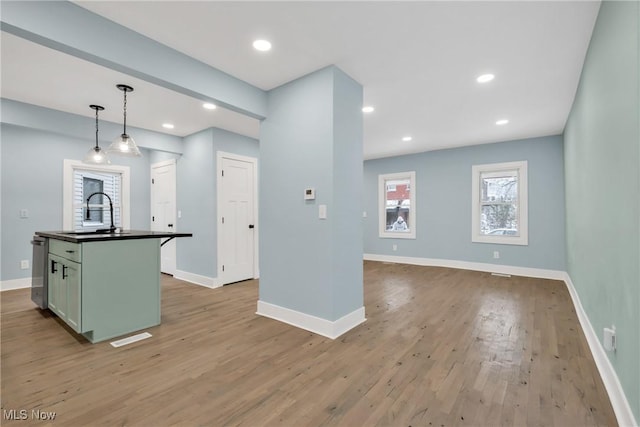 kitchen with dark countertops, baseboards, a sink, and light wood finished floors