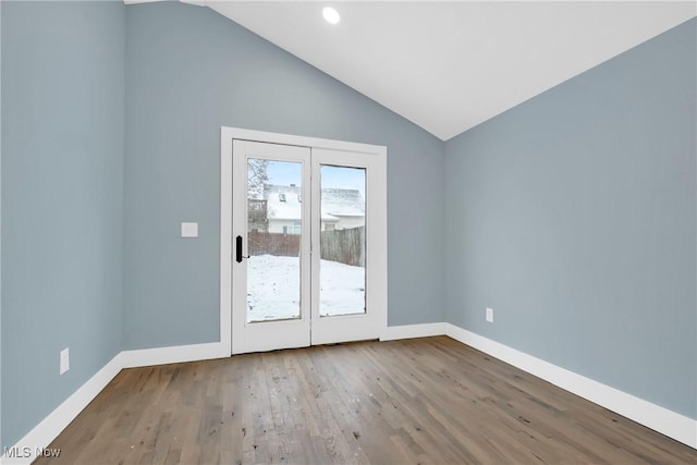 empty room featuring lofted ceiling, wood finished floors, and baseboards