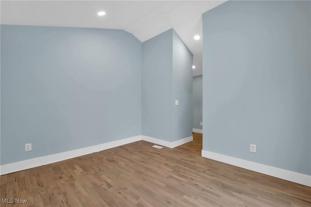 unfurnished room featuring vaulted ceiling, recessed lighting, wood finished floors, and baseboards