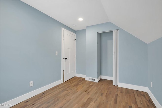 additional living space featuring visible vents, vaulted ceiling, baseboards, and wood finished floors