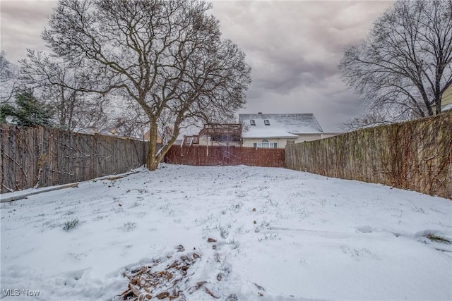 snowy yard featuring a fenced backyard