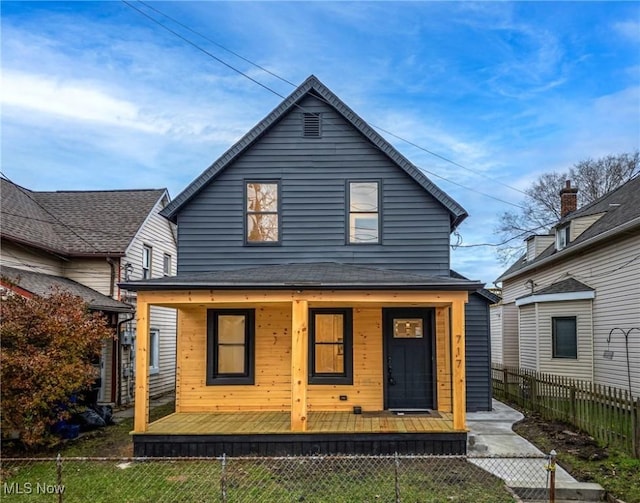 rear view of property featuring a fenced front yard and covered porch