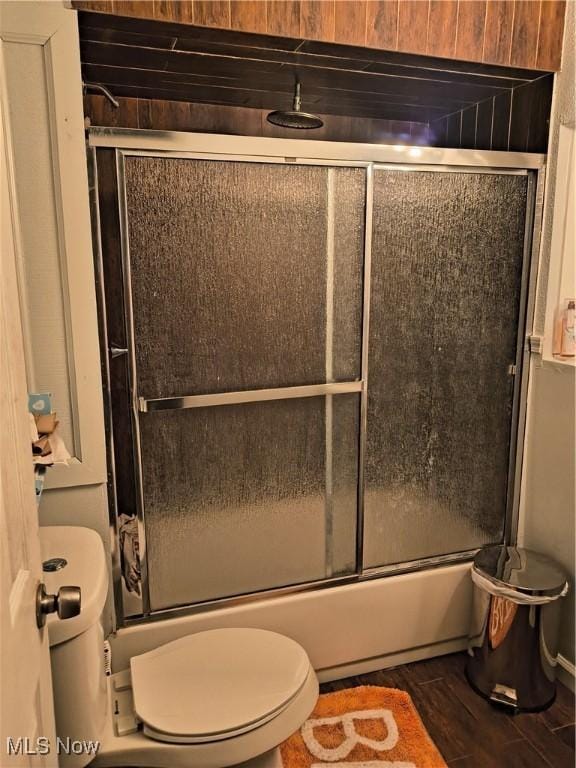 bathroom featuring enclosed tub / shower combo, toilet, and hardwood / wood-style floors