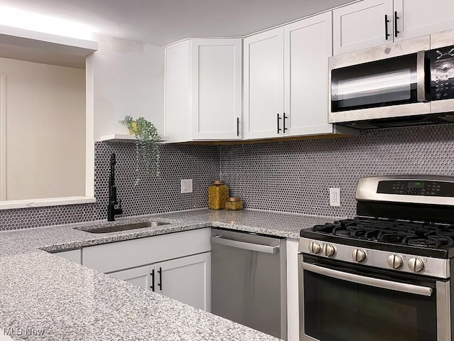 kitchen with backsplash, white cabinetry, sink, and appliances with stainless steel finishes