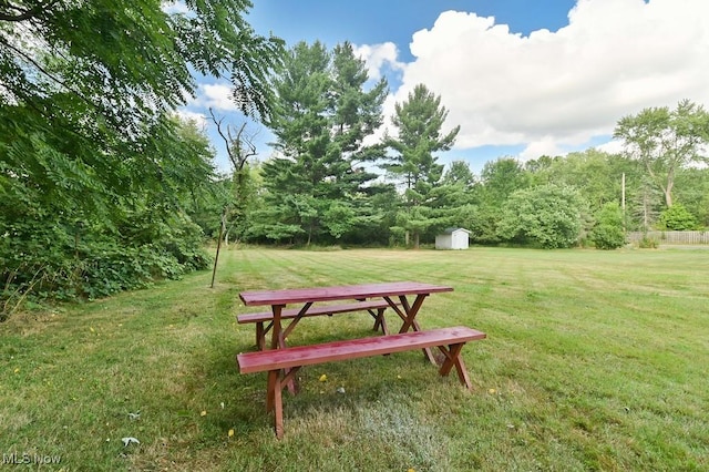 view of property's community featuring a lawn and a storage shed