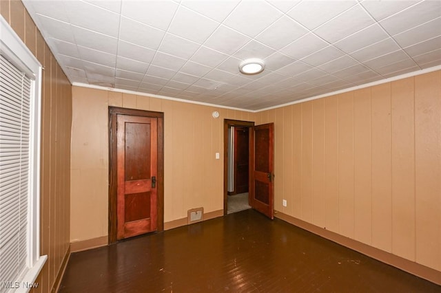 empty room with dark hardwood / wood-style floors and crown molding