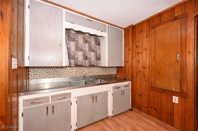 kitchen featuring backsplash, sink, a textured ceiling, and light hardwood / wood-style flooring