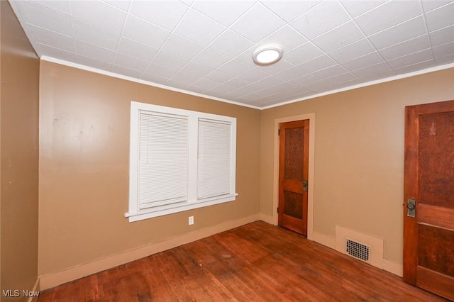 empty room featuring hardwood / wood-style floors and ornamental molding