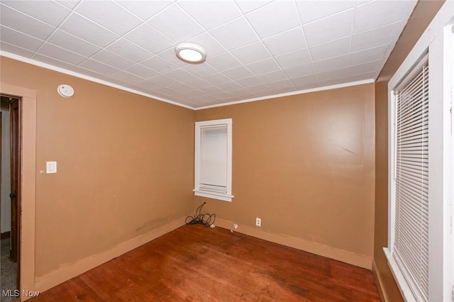 empty room with wood-type flooring and crown molding