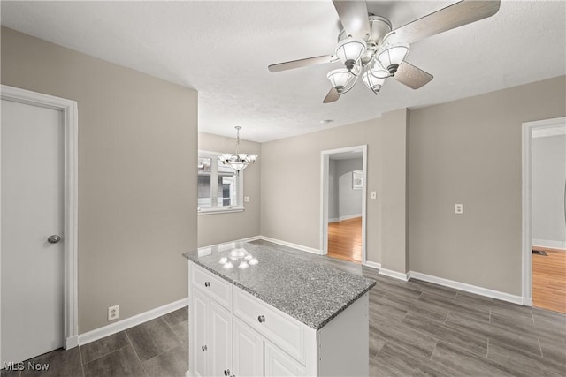 kitchen with ceiling fan with notable chandelier, light stone countertops, a textured ceiling, dark hardwood / wood-style flooring, and white cabinetry