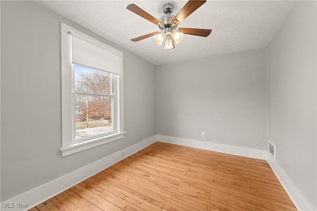 spare room featuring ceiling fan, light hardwood / wood-style floors, and a textured ceiling