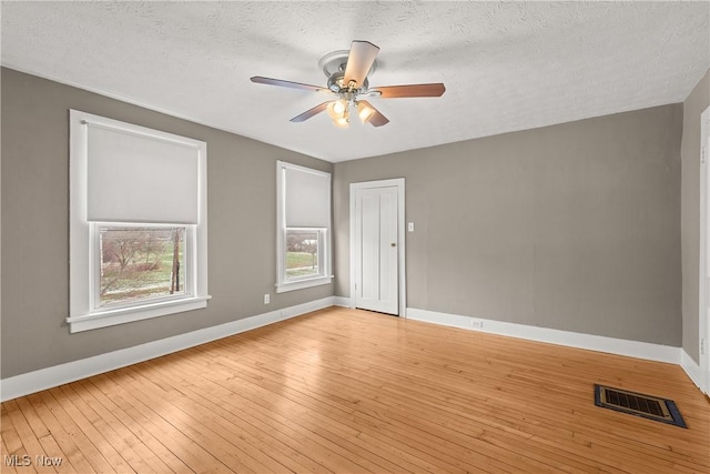 empty room with a textured ceiling, light hardwood / wood-style flooring, and ceiling fan