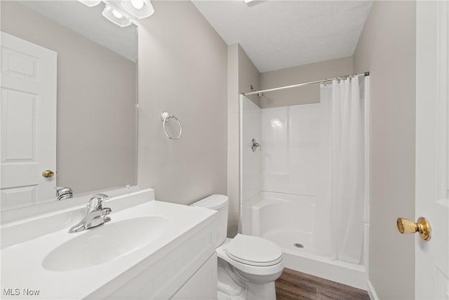 bathroom featuring vanity, toilet, a textured ceiling, walk in shower, and wood-type flooring